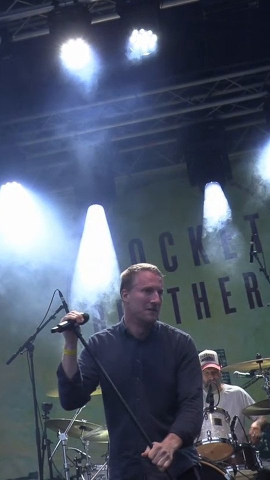 Jacob Friis synger, med trommeslager og banner i baggrunden